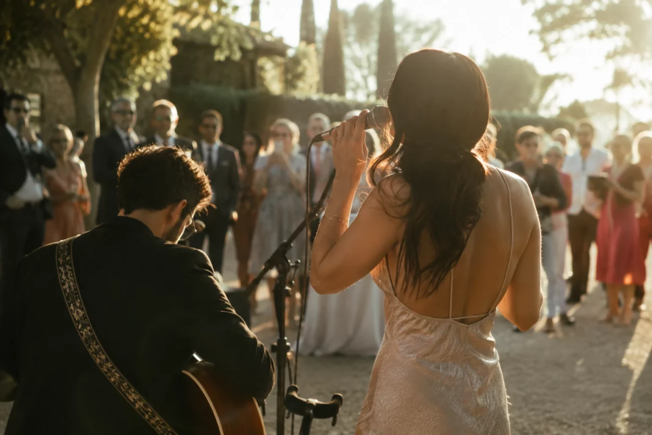 Duo de musiciens en live lors d’un mariage en extérieur, chanteuse et guitariste devant les invités